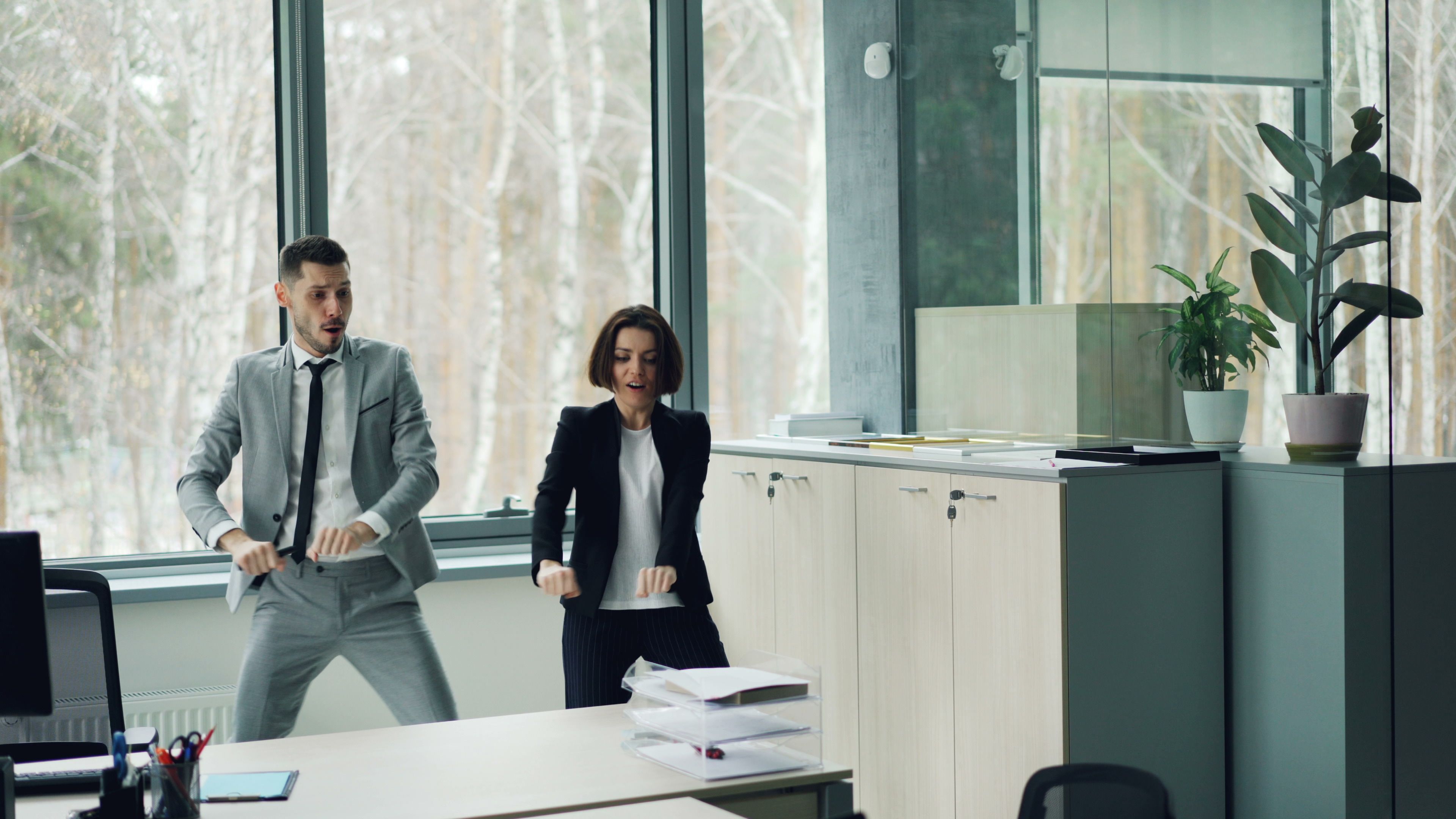 Zwei Mitarbeitende tanzen im Büro
